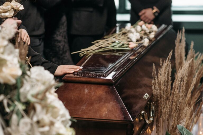 A poignant funeral moment with mourners gathered around a coffin decorated with flowers.